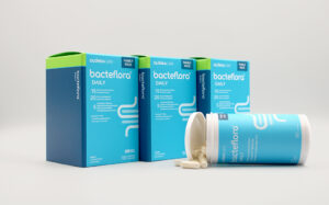 Blue Bacteflora Daily probiotic boxes lined up with a bottle and loose capsules on a white surface.
