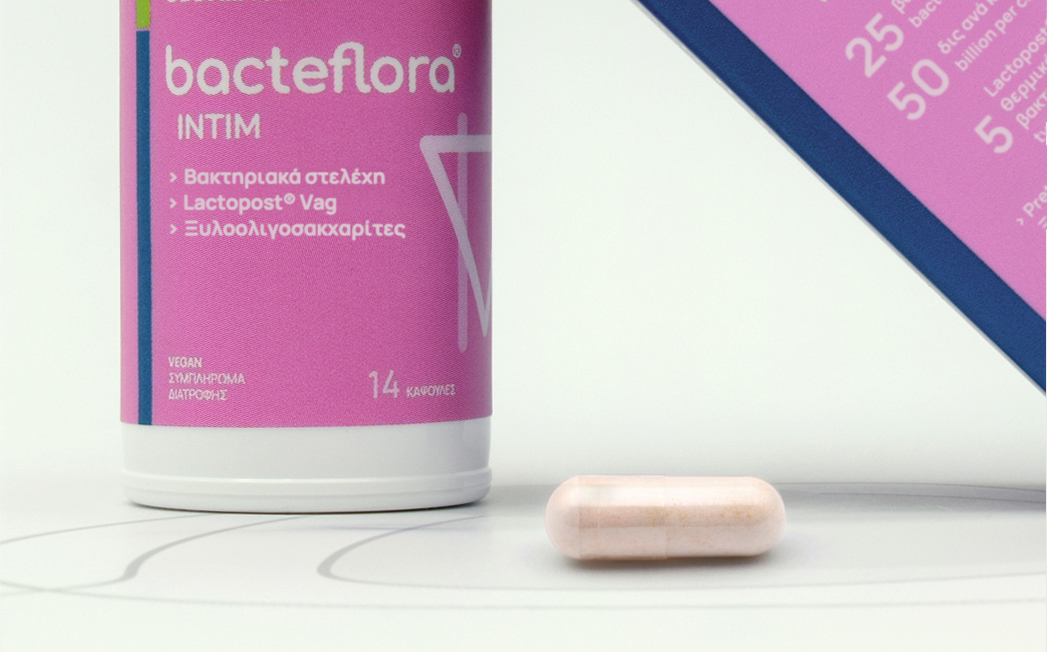 Pink Bacteflora Intim probiotic bottle with a pale pink capsule on a white surface and a pink box nearby.