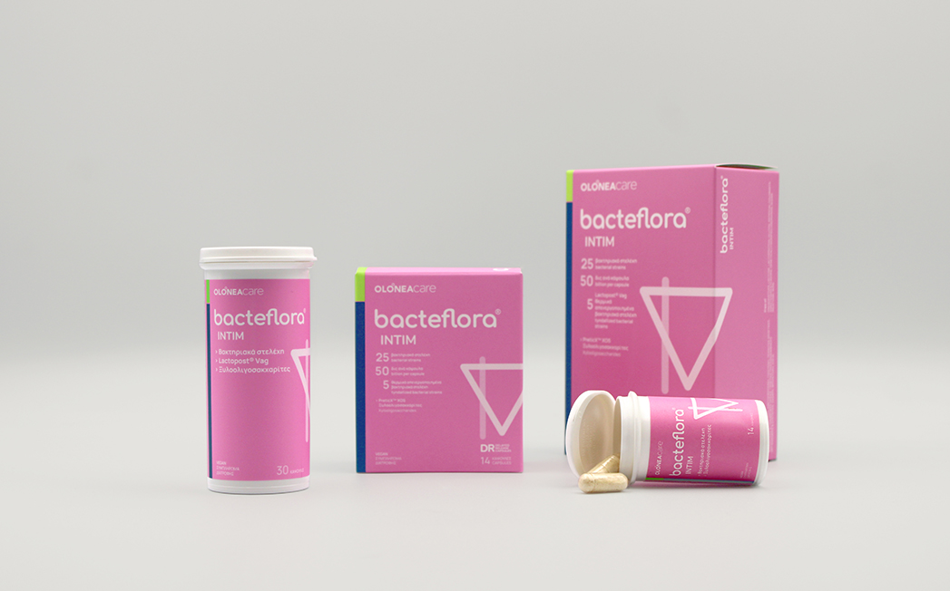 Set of pink Bacteflora Intim packaging (boxes, bottle) with capsules on a light gray surface.