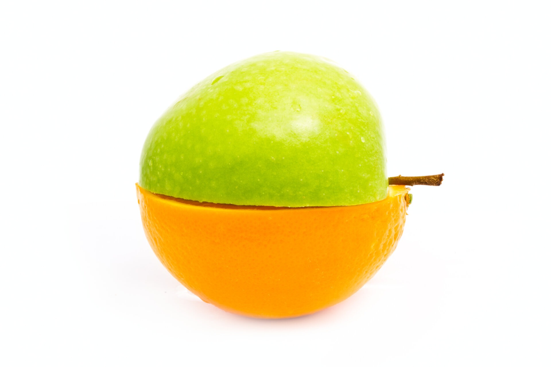 Μισό πράσινο μήλο, το οποίο εφάπτεται από την εσωτερική, κομμένη του πλευρά, με ένα μισό πορτοκάλι.