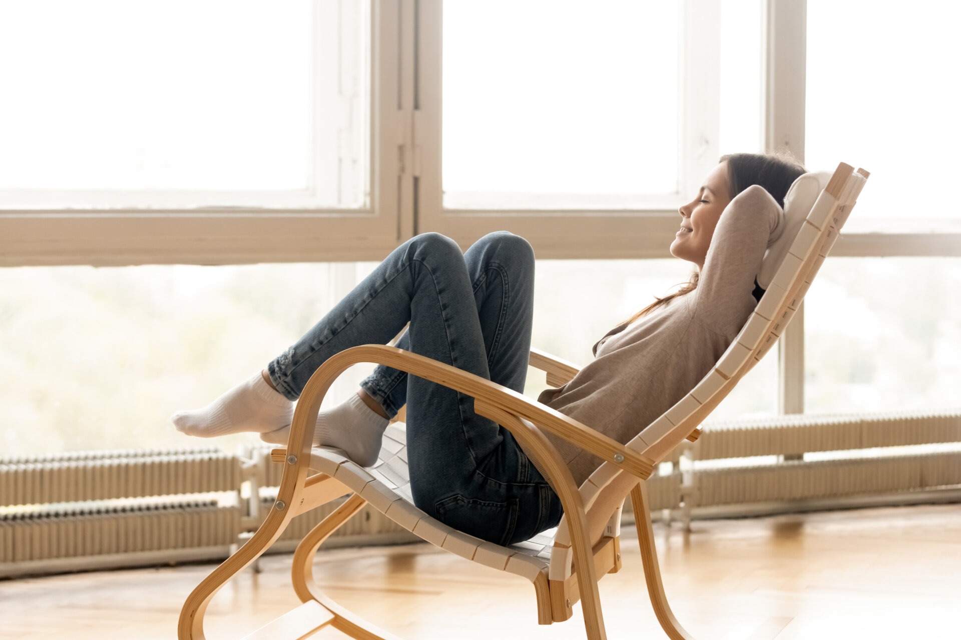 Μια γυναίκα που κάθεται σε μια κουνιστή καρέκλα και φαίνεται να χαλαρώνει και να είναι ξεκούραστη κι ανέμελη.