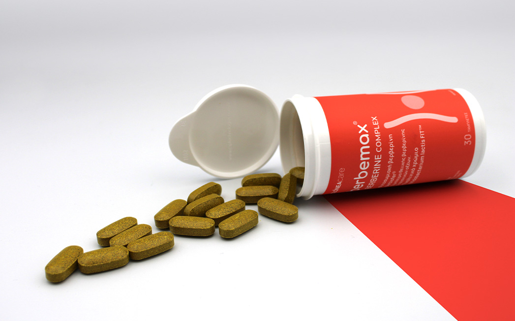 Red prescription bottle tipped over with brown oblong tablets spilled onto a white surface.