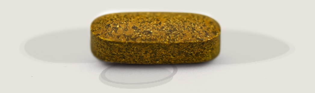 Brown speckled tablet on a white surface with soft shadows above and below it.
