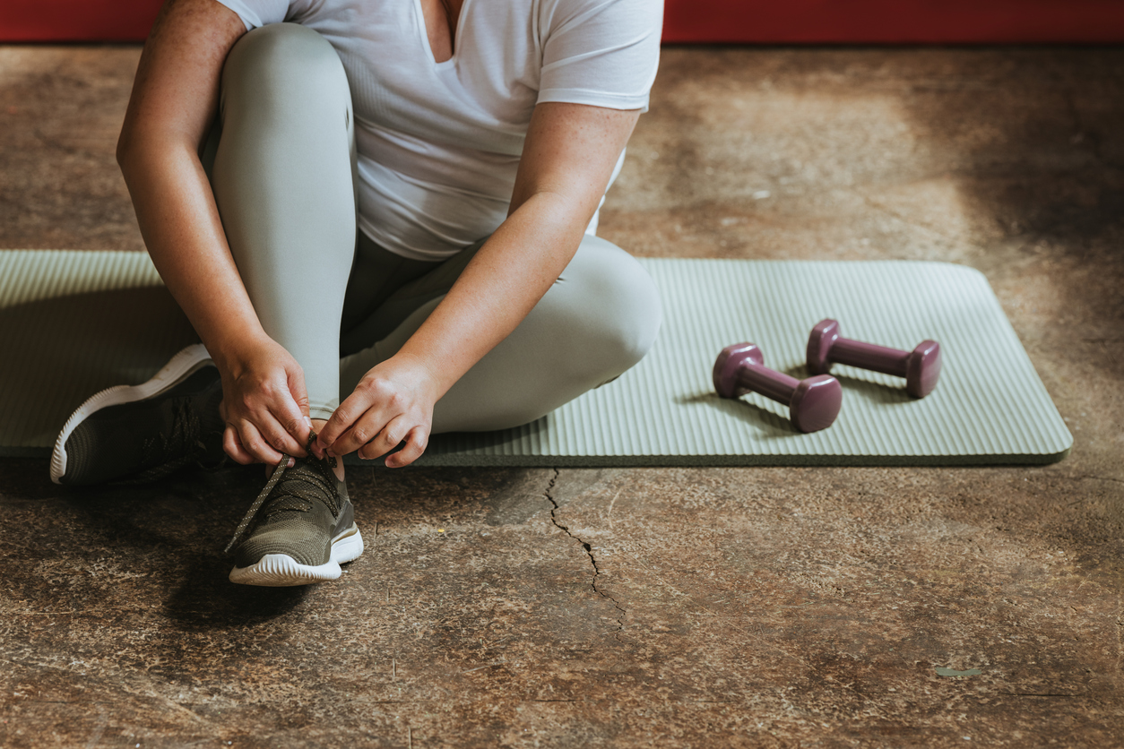 Μια γυναίκα σε ένα χαλάκι yoga, με ένα ζευγάρι βαράκια δίπλα της, η οποία γυμνάζεται προσπαθώντας να διατηρήσει μια ισορροπία στον οργανισμό της και να αποφύγει το μεταβολικό σύνδρομο.