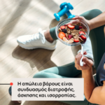 Άτομο σε γυμναστήριο/σπίτι, τρώει μπολ δημητριακών με φρούτα (φράουλες, μύρτιλα) ενώ υπάρχουν αλτήρες στο παρασκήνιο — μήνυμα ότι η απώλεια βάρους εξαρτάται από διατροφή, άσκηση και ισορροπία.