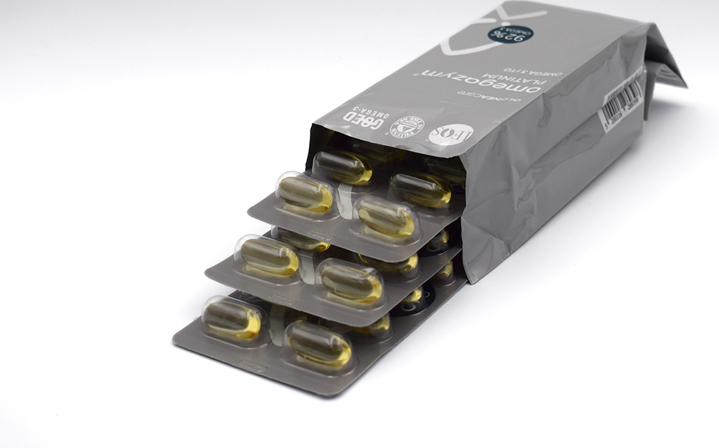 Blister packs with yellow gel capsules spilling from a gray foil medicine pouch.
