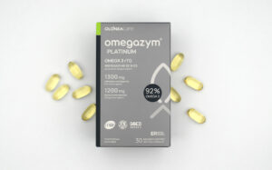 Omega-3 Platinum supplement box with yellow softgel capsules scattered around on a light surface.